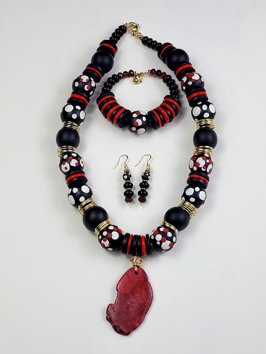 Matte black polka-dot beaded necklace with red disc spacers and a red stone slab pendant.