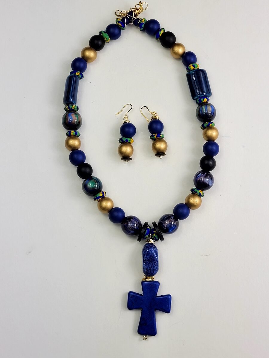 Royal blue beaded necklace with matte black beads, gold rondelles, and millefiori accents, finished with a blue cross pendant.